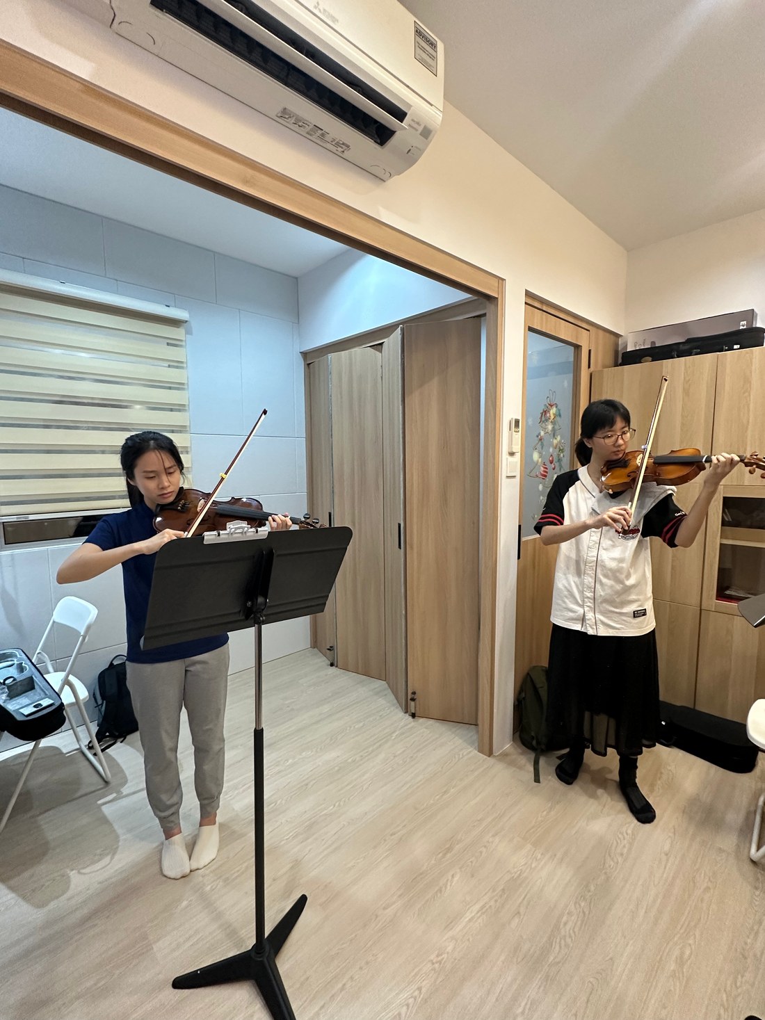 Two young violin students playing in a lesson room